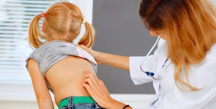 el médico revisa la espalda del niño para detectar dolor de espalda